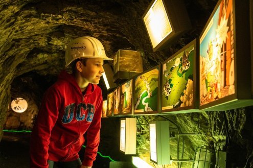 Junge mit Helm schaut sich in einem unterirdischen Tunnel etwas an