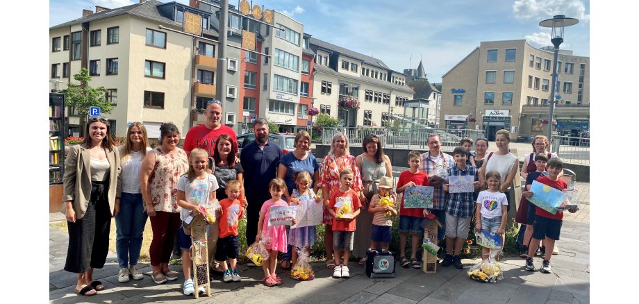 Erwachsene und Kinder stehen zu einem Gruppenbild zusammen - die Kinder halten ihre Bilder in der Hand