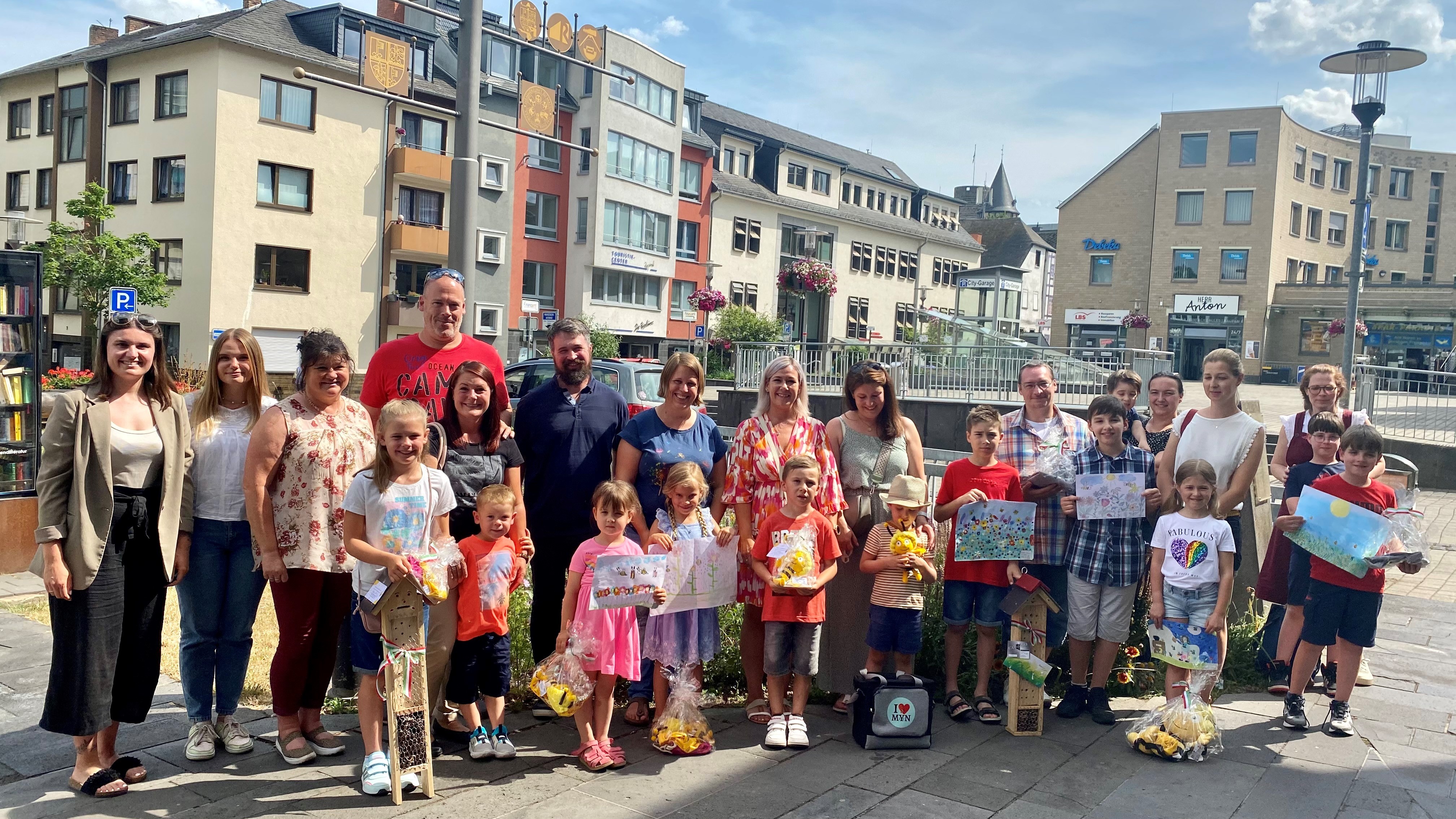 Erwachsene und Kinder stehen zu einem Gruppenbild zusammen - die Kinder halten ihre Bilder in der Hand