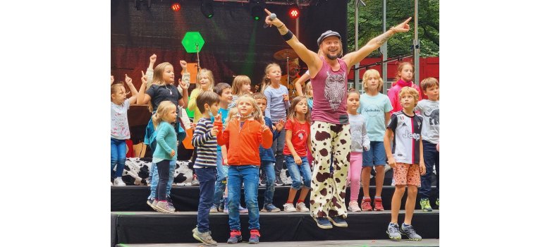 Maxim Wartenberg und sein Trommelfloh beim Stadtfest mit dabei Ein Erwachsener und viele Kinder auf einer Bühne. Es wird gesprungen