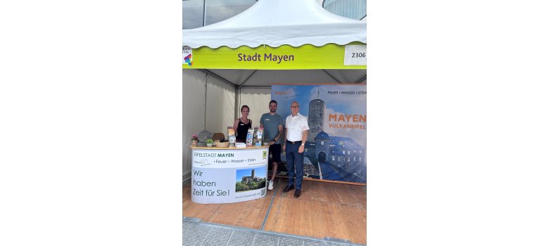 3 Personen stehen unter einem Pavillon der Stadt Mayen hinter einer kleinen Theke