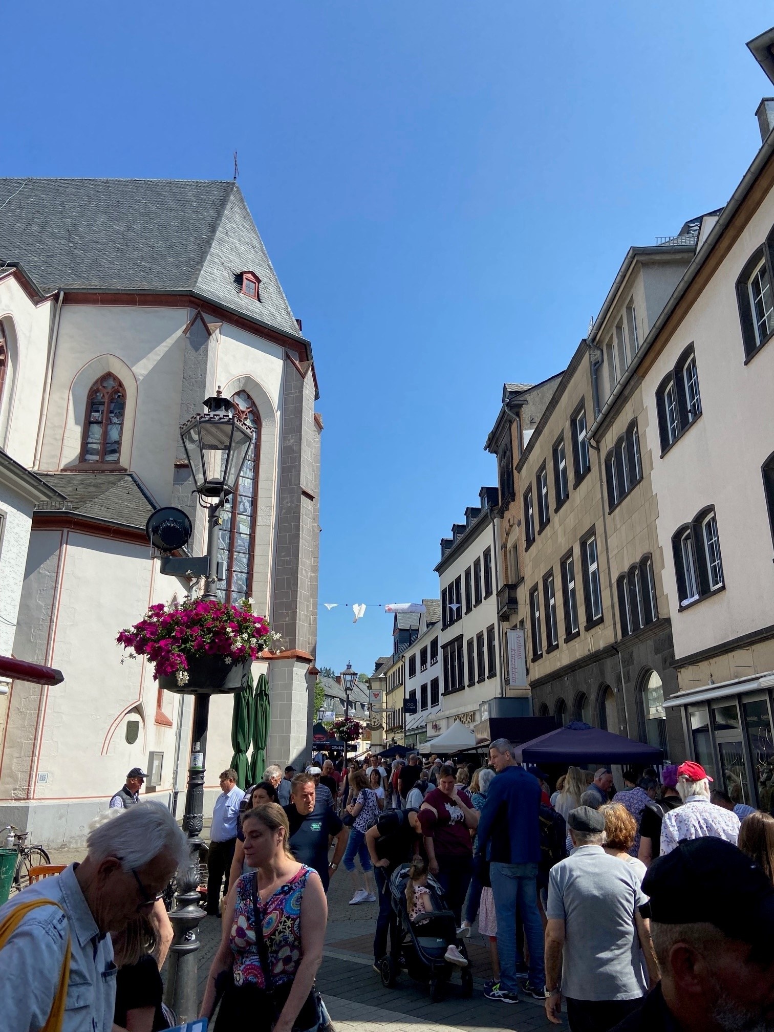 Viele Menschen in der Mayener Marktstraße bei blauem Himmel