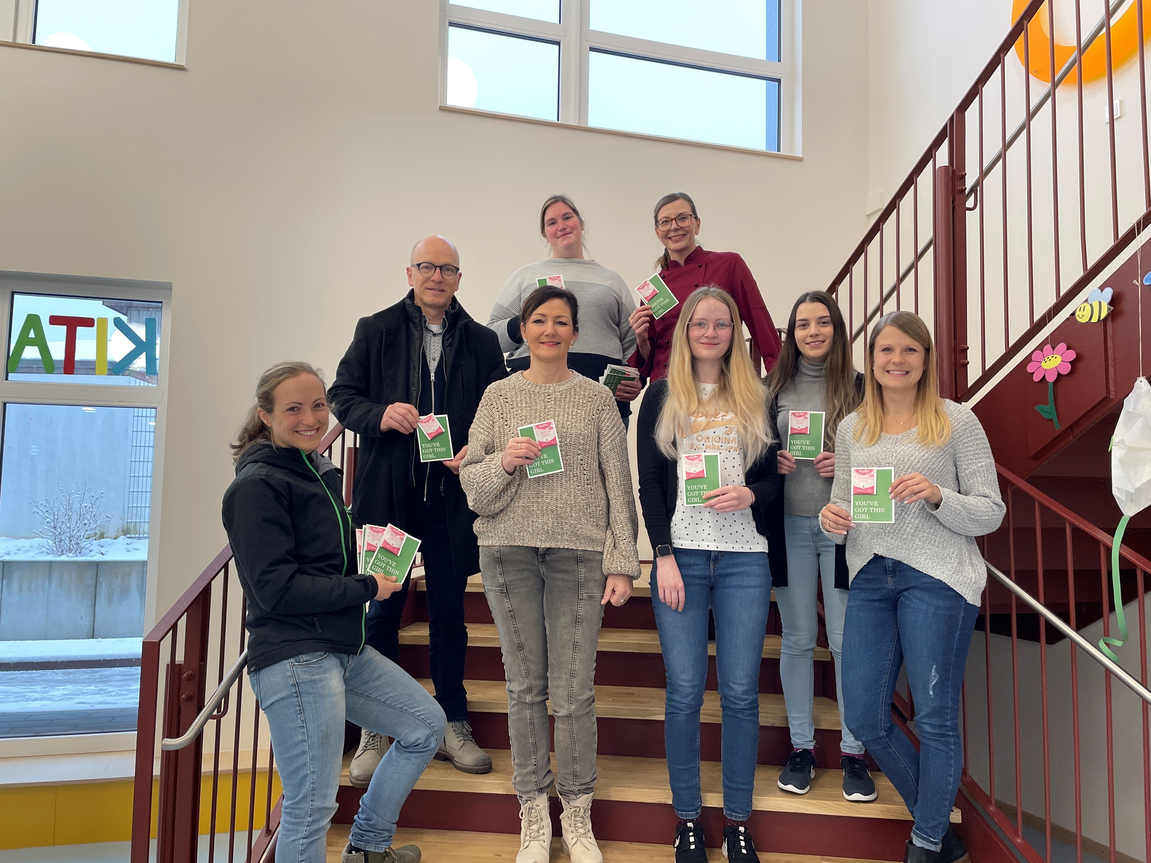 8 Personen stehen auf einer Treppe und halten eine Karte in der Hand