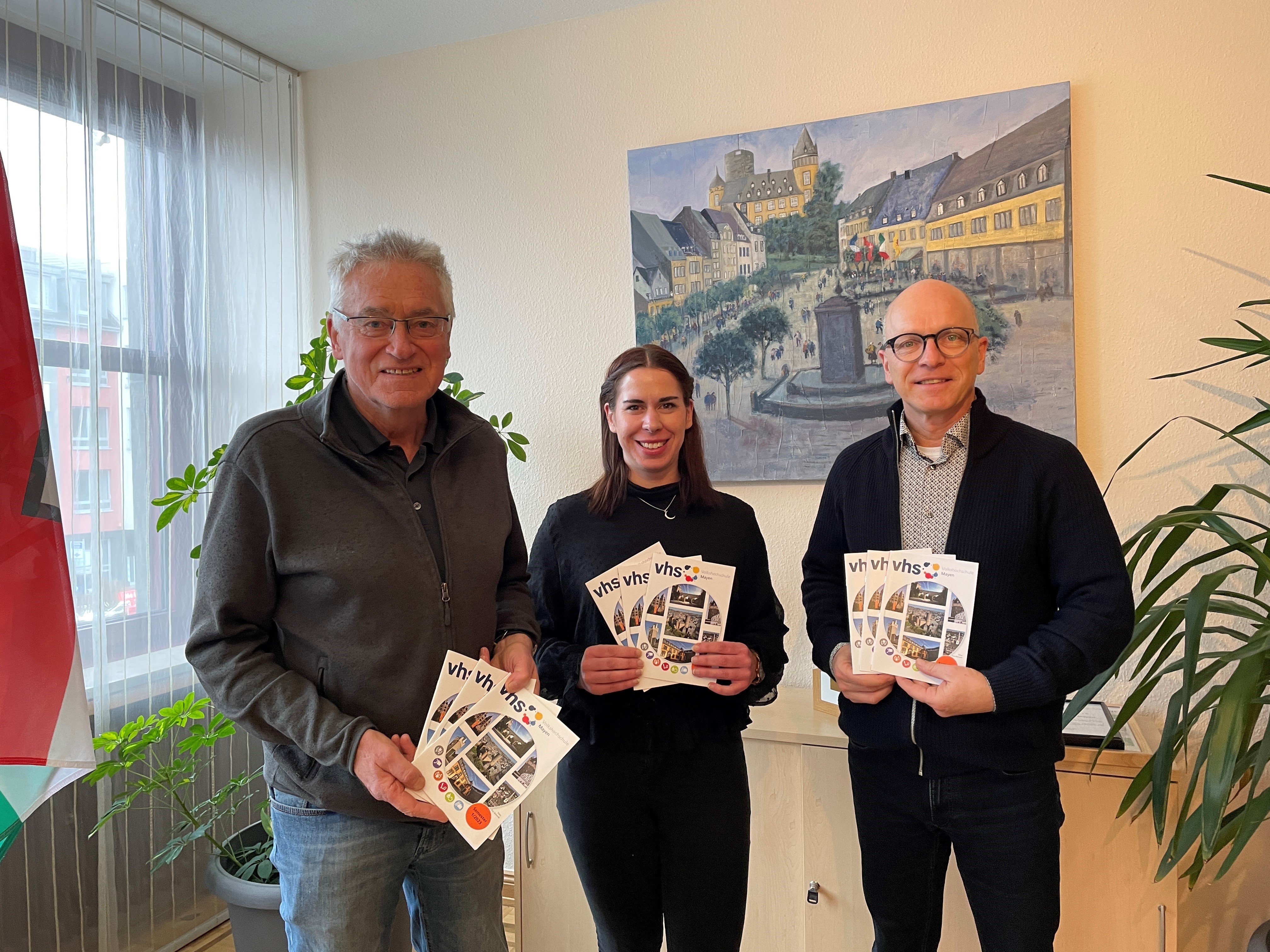 Josef Brodam pädagogischer Leiter der VHS, Yvonne Müller Stellvertretung der Geschäftsstelle der VHS und Oberbürgermeister Dirk Meid stehen in einem Büro des Rathauses und halten Programmhefte in den Händen