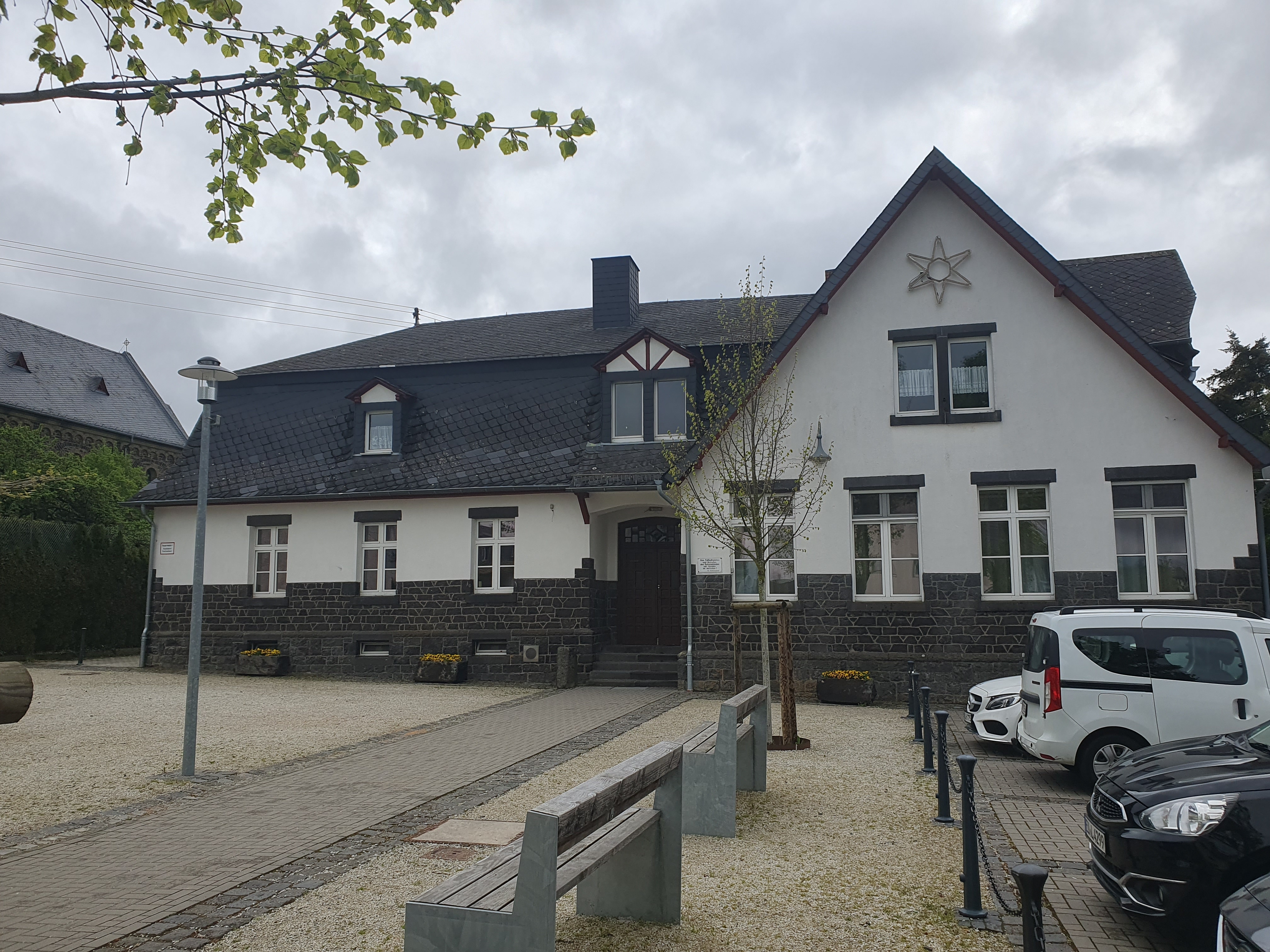 Bild von einem Haus, an der Seite stehen Autos