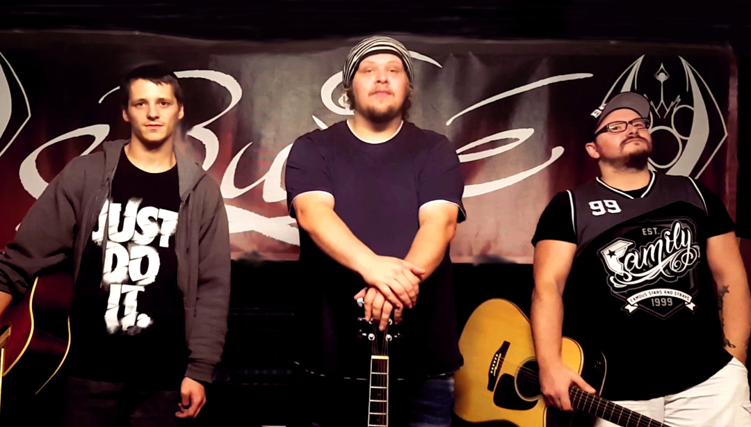 3 Musiker stehen mit ihren Instrumenten vor einer Wand