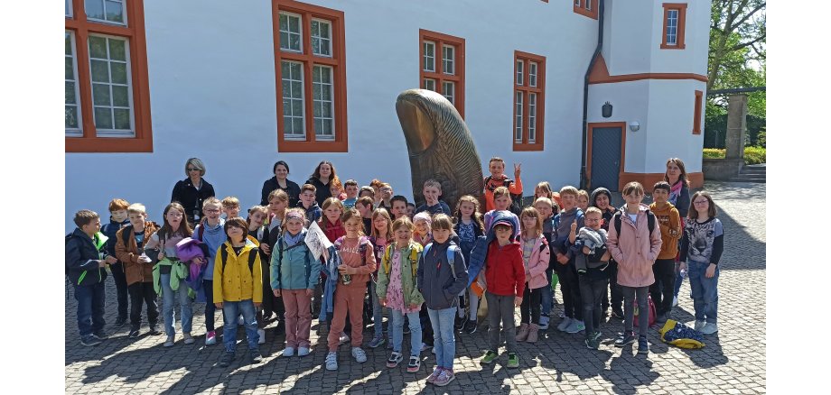 Eine Gruppe von Kindern steht an einer Statue zu einem Gruppenfoto zusammen