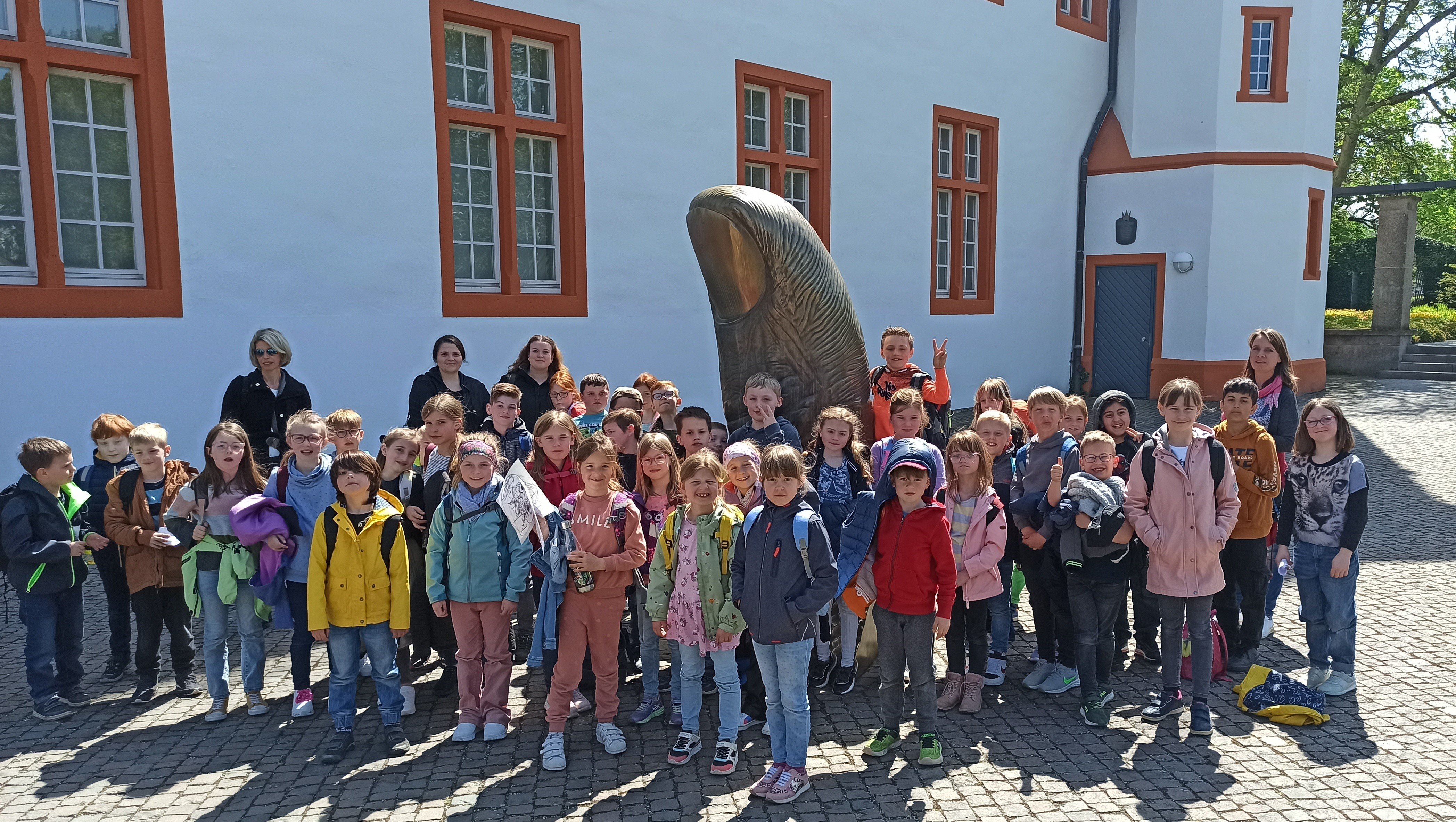 Eine Gruppe von Kindern steht an einer Statue zu einem Gruppenfoto zusammen
