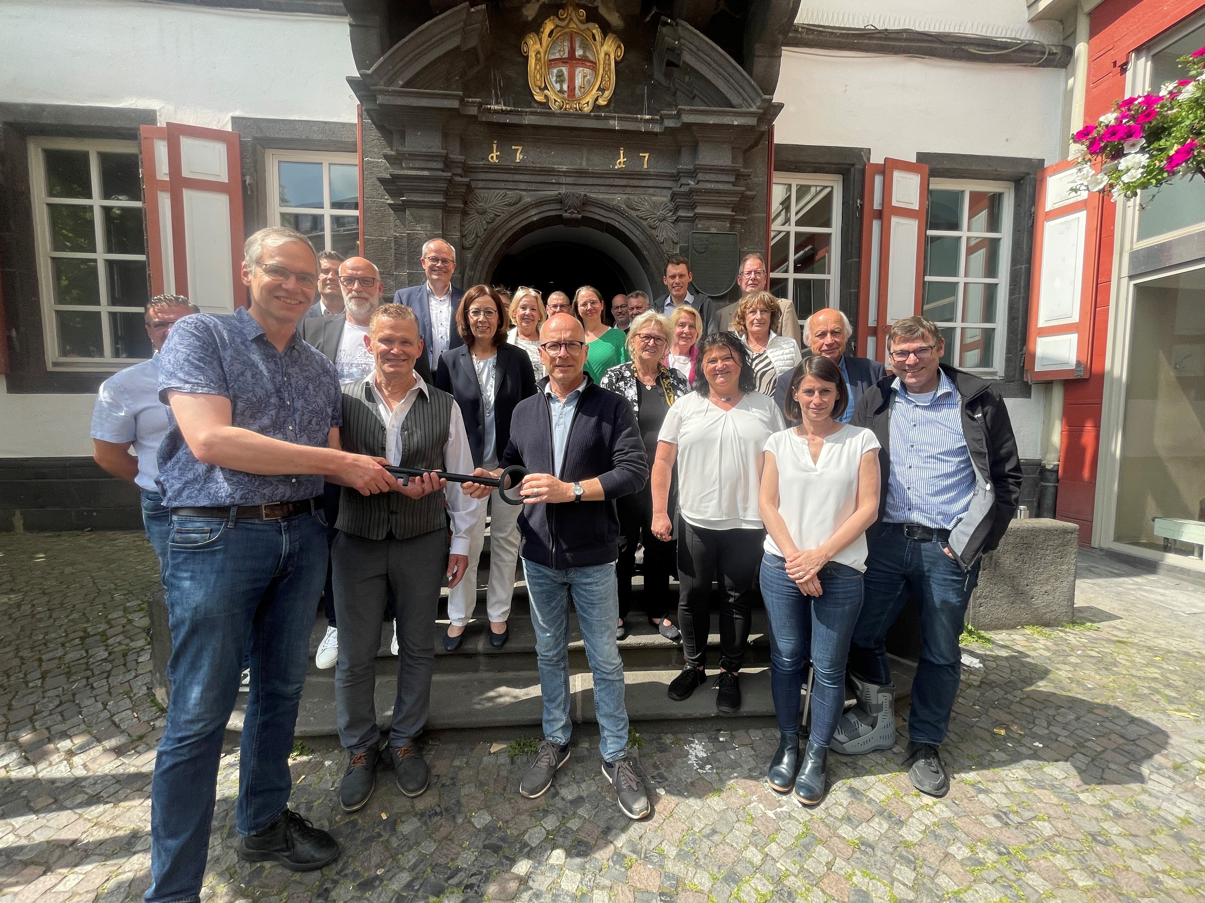 Gruppe von Personen vor dem Alten Rathaus - 2 Personen übergeben sich einen symbolischen Schlüssel