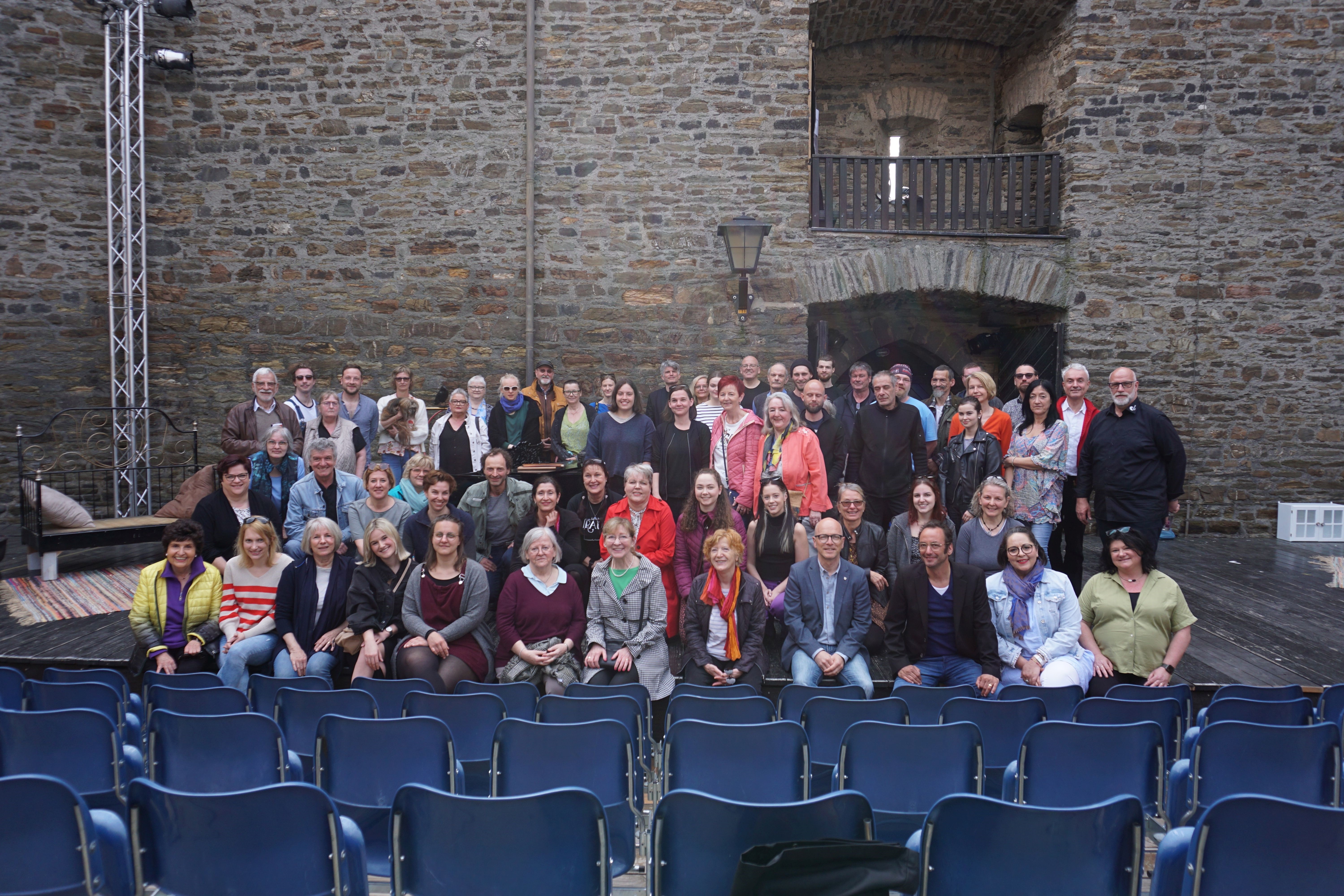 Eine Gruppe von Menschen steht auf einer Bühne zu einem Gruppenfoto zusammen