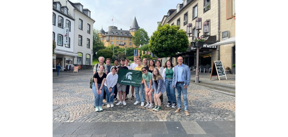 Eine Gruppe Studierende stehen auf dem Marktplatz zusammen - es wird eine Fahne hochgehalten