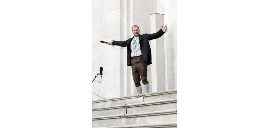 Thomas Limpinsel tritt mit „Jedermann – leicht gekürzt“ beim Stadtfest „KulturGenuss“ auf Mann steht auf einer Treppe und wirft die Arme nach oben