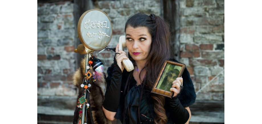 Frau mit Telefon am Ohr und einem Bild in der Hand - danach ein Schild mit der Aufschrift Orakel to Go