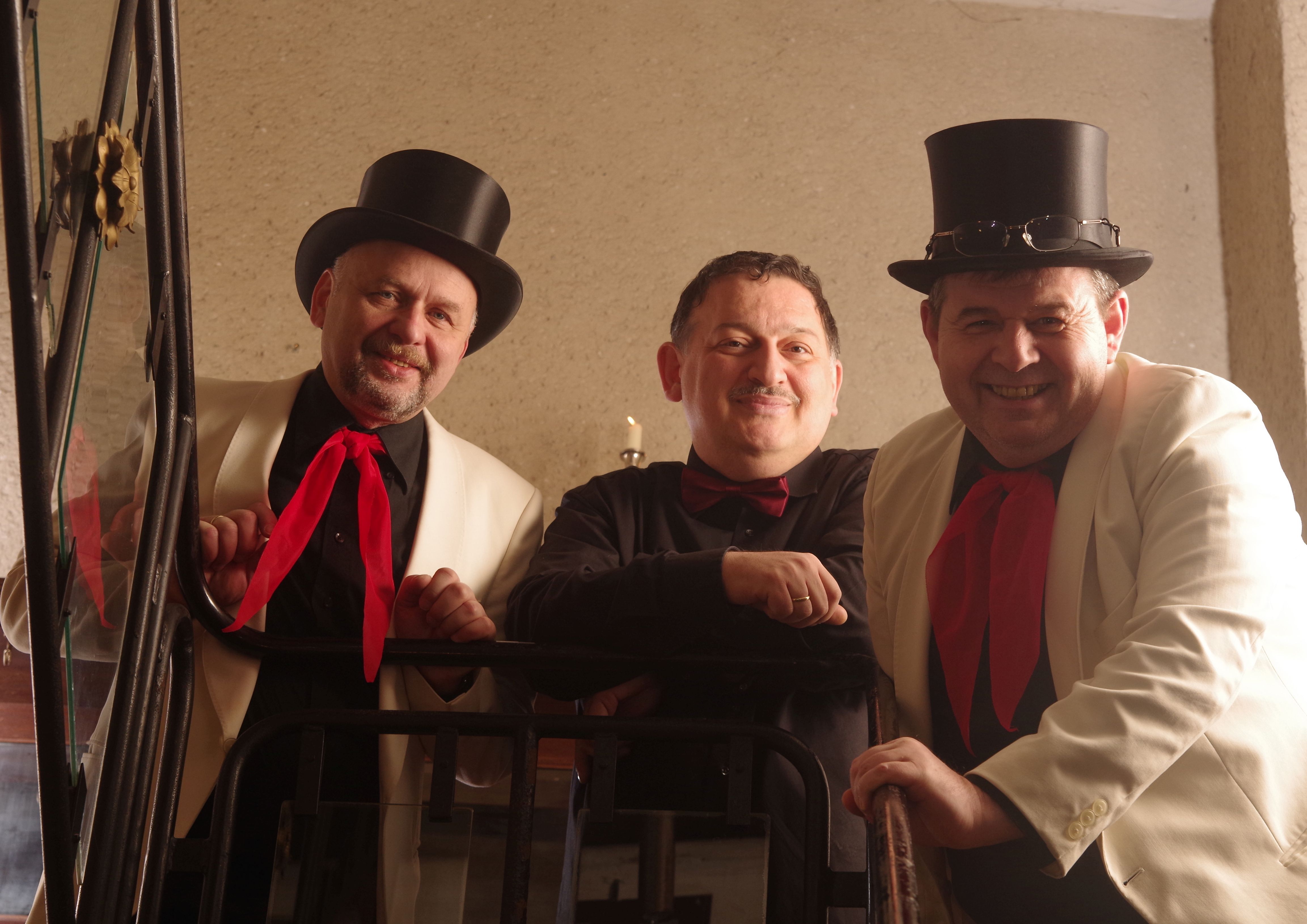 3 Männer stehen zusammen - zwei davon tragen einen Zylinder