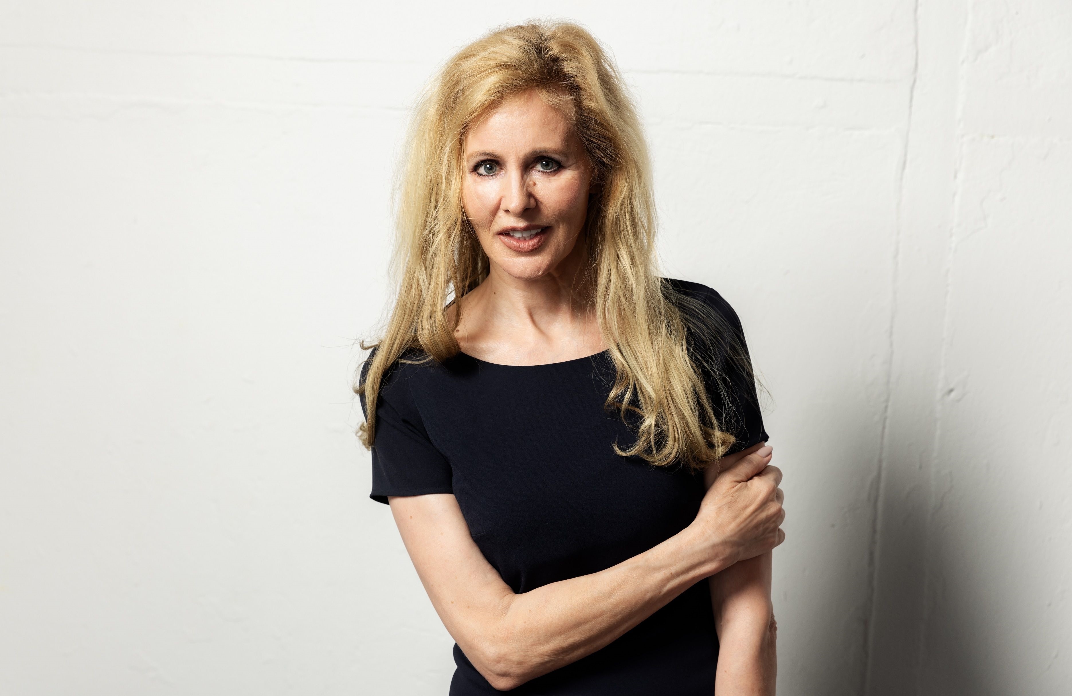 Ein blonde Frau steht vor weißem Hintergrund