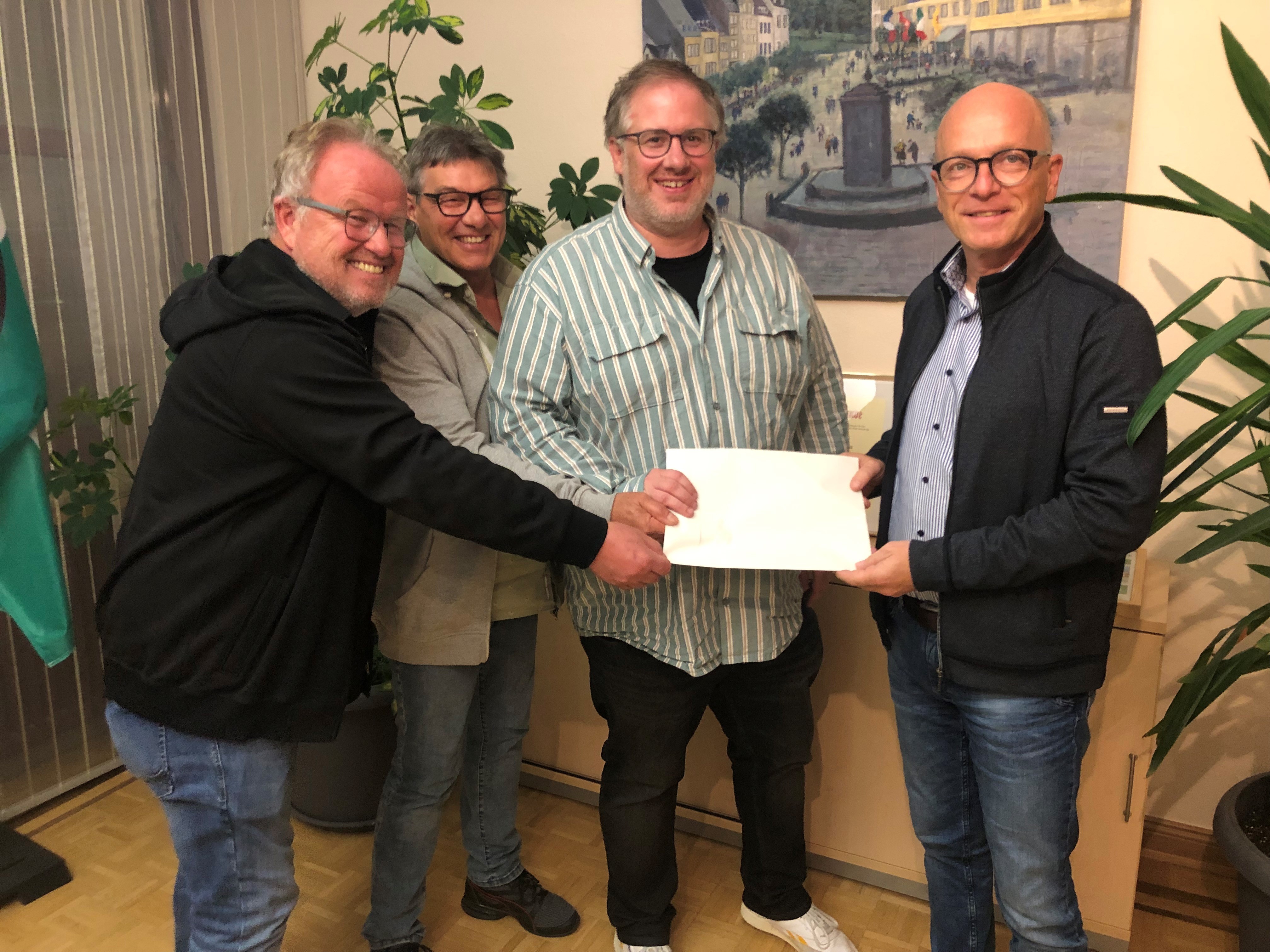 4 Personen halten einen Scheck in der Hand