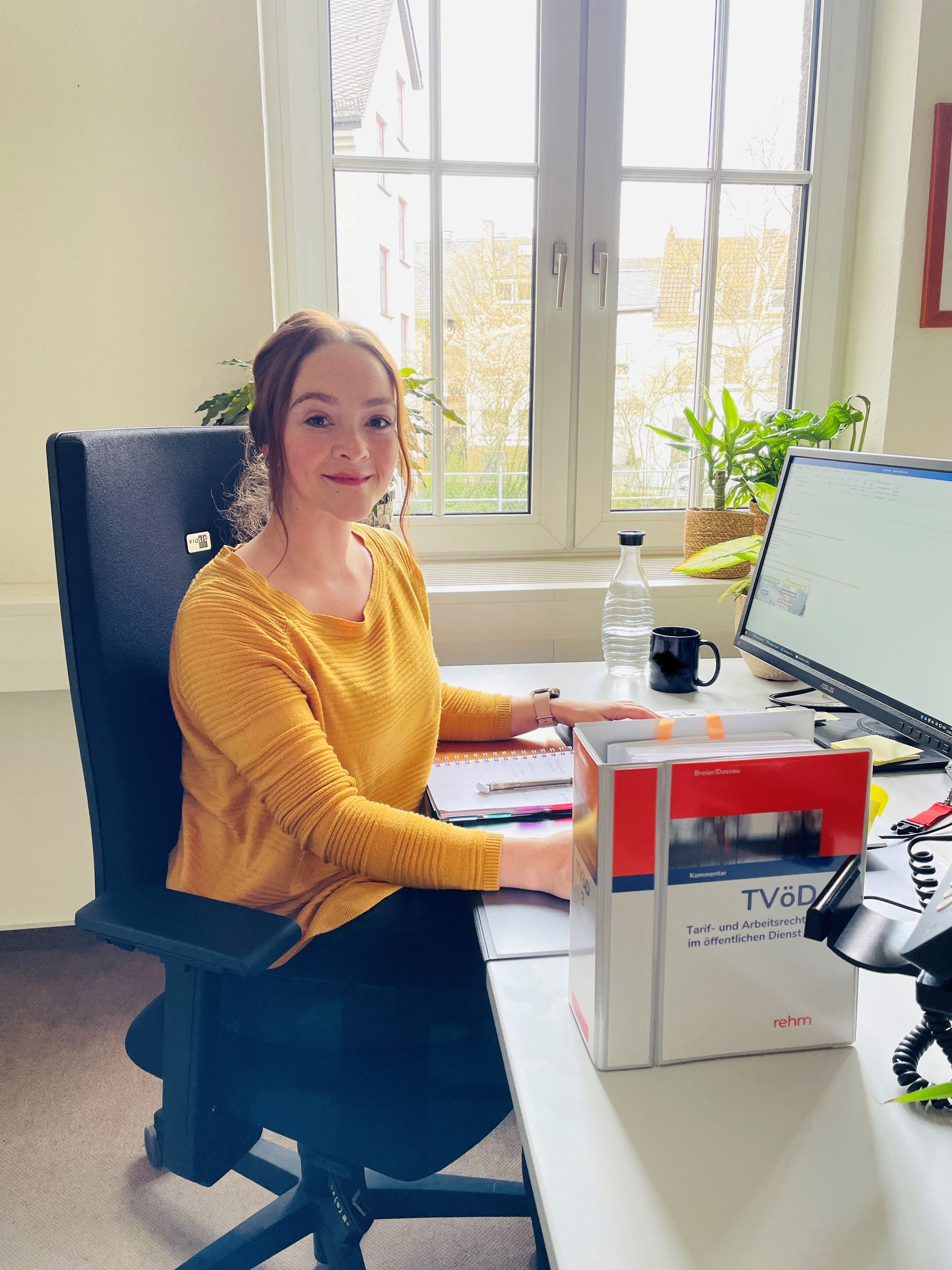 Eine Frau sitzt an Ihrem Arbeitsplatz - vor Ihr stehen Gesetztestexte