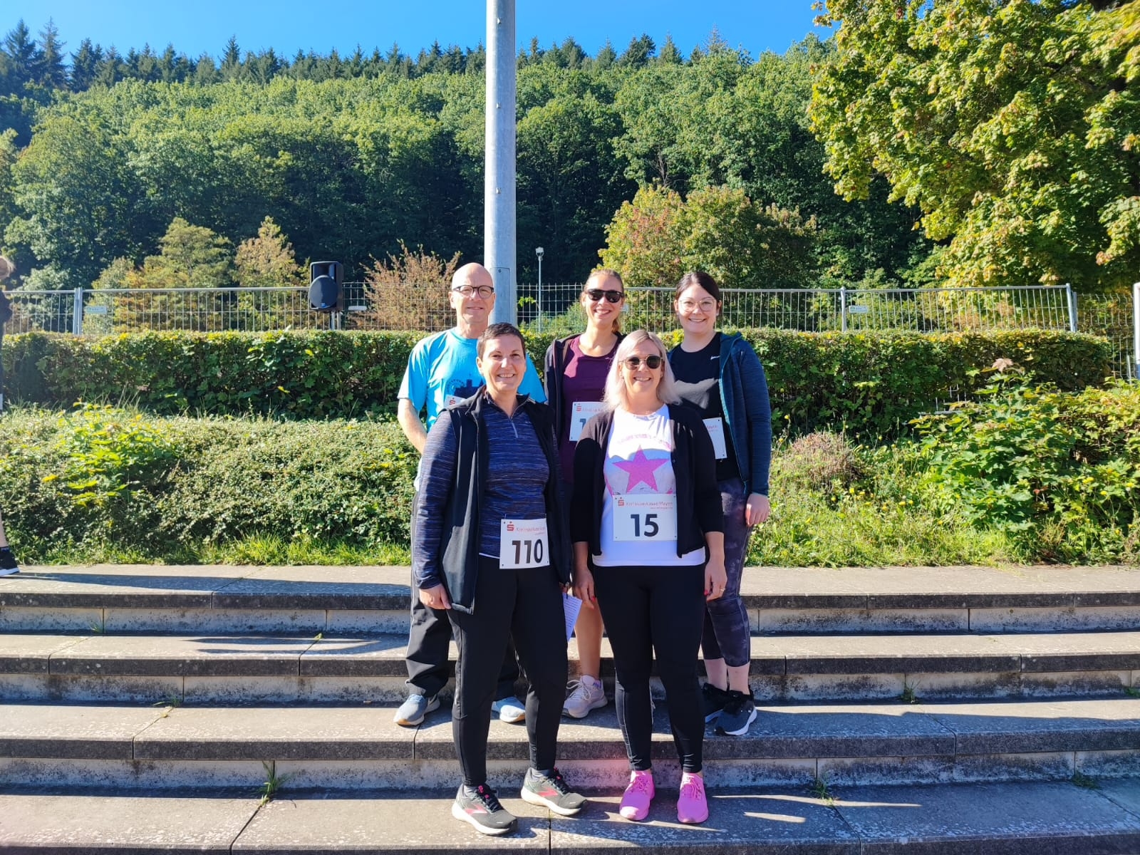 Die motivierten Läufer*innen der Stadt Mayen freuen sich auf den Start Fünf Personen auf einer Treppe im Nettestadion