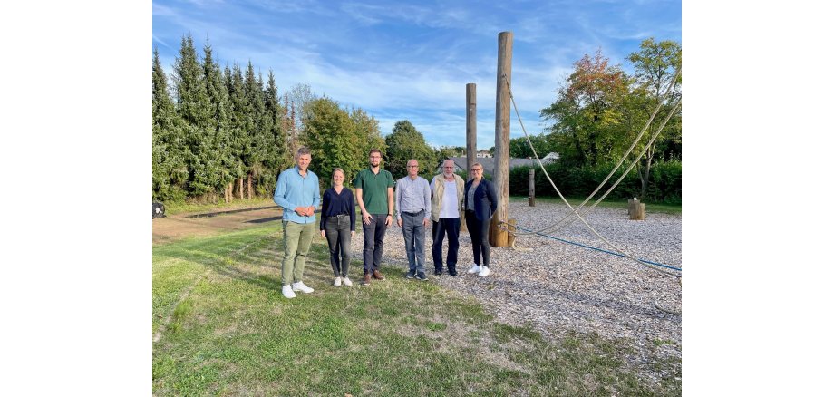 6 Personen stehen neben einem Niedrigseilparcours für ein Bild zusammen