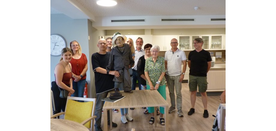 Mehrere Personen stehen für ein Bild zusammen - einer hält die Puppe des Zuckertoni