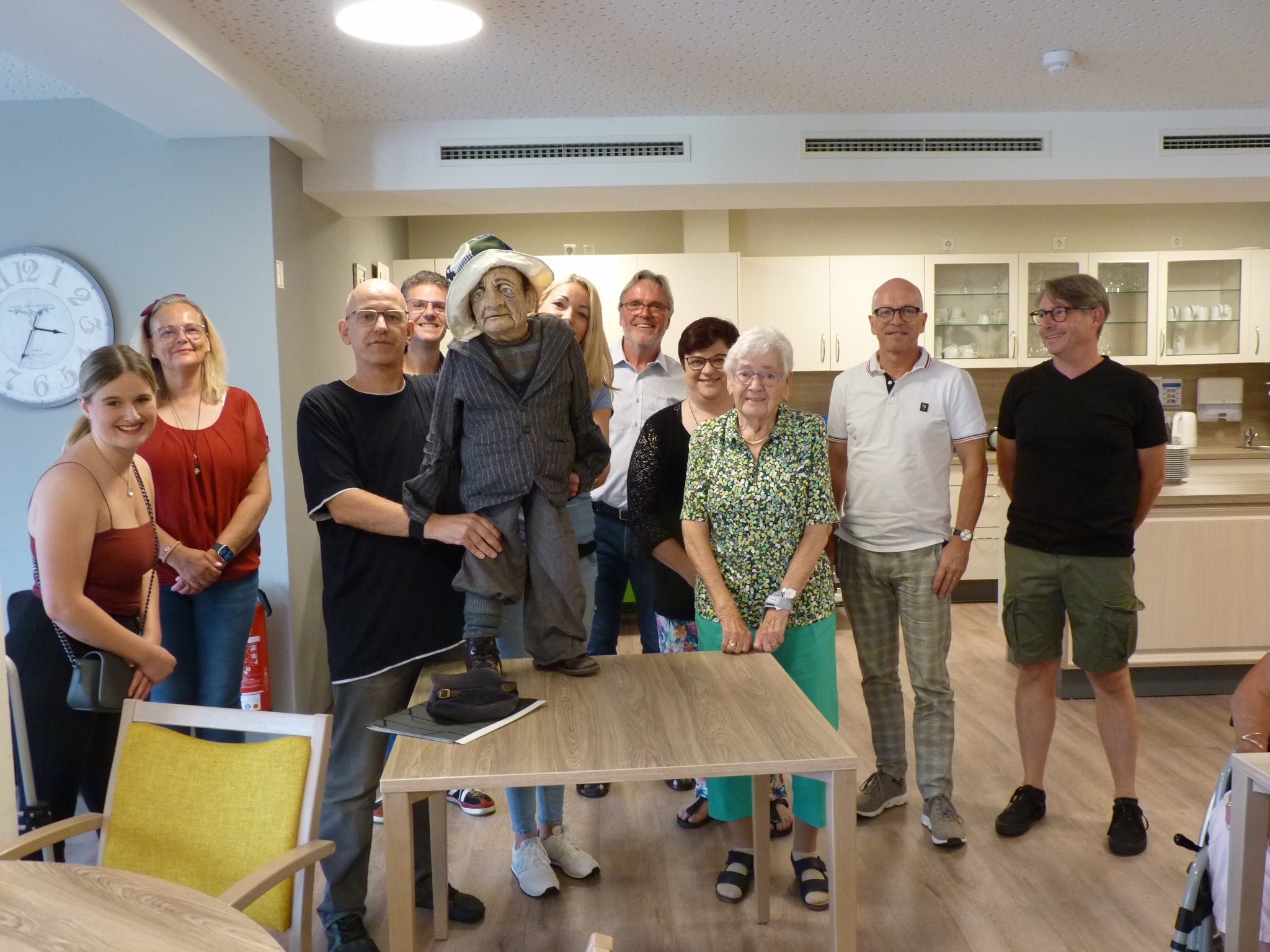 Mehrere Personen stehen für ein Bild zusammen - einer hält die Puppe des Zuckertoni