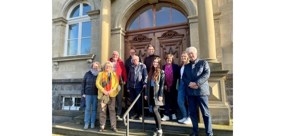 Gruppe von Menschen steht vor einem Gebäude auf einer Treppe