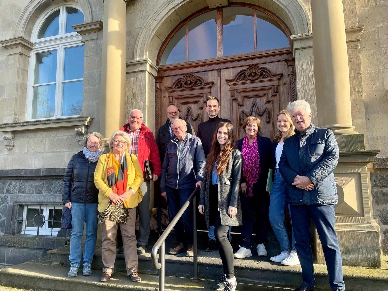 Gruppe von Menschen steht vor einem Gebäude auf einer Treppe