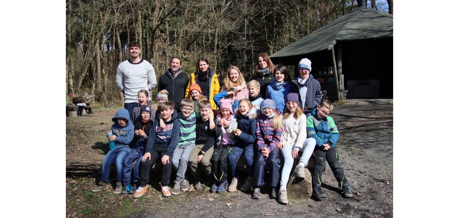 Kinder sitzen vor einer Waldhütte für ein Bild zusammen 