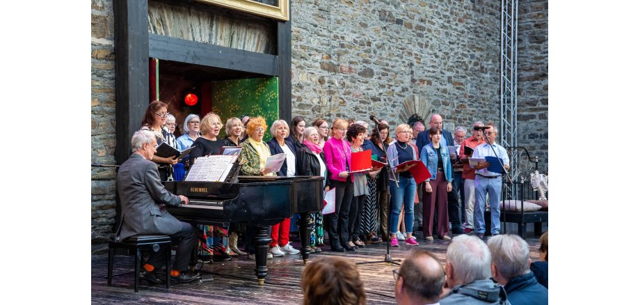 Mehrere Personen stehen auf einer Bühne und singen