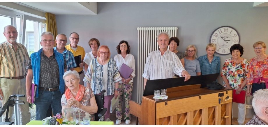 Mehrere Personen stehen zusammen, in der Mitte ein Klavier