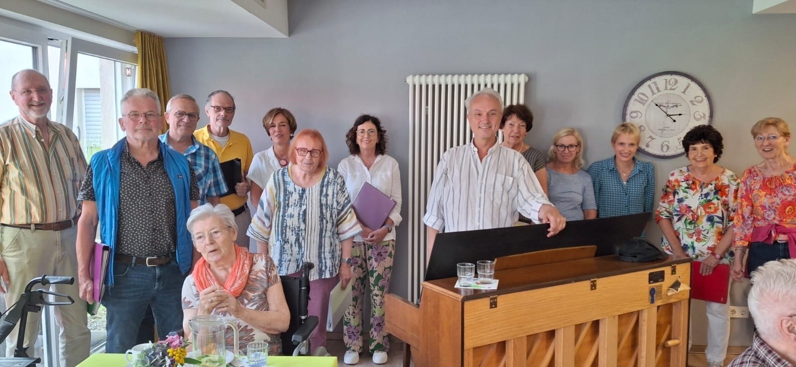 Mehrere Personen stehen zusammen, in der Mitte ein Klavier