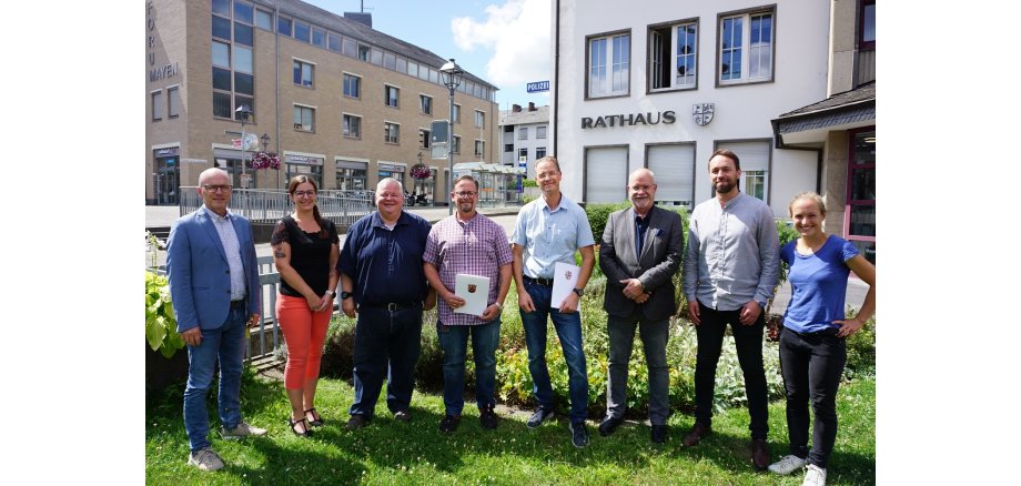 8 Personen stehen vor dem Rathaus