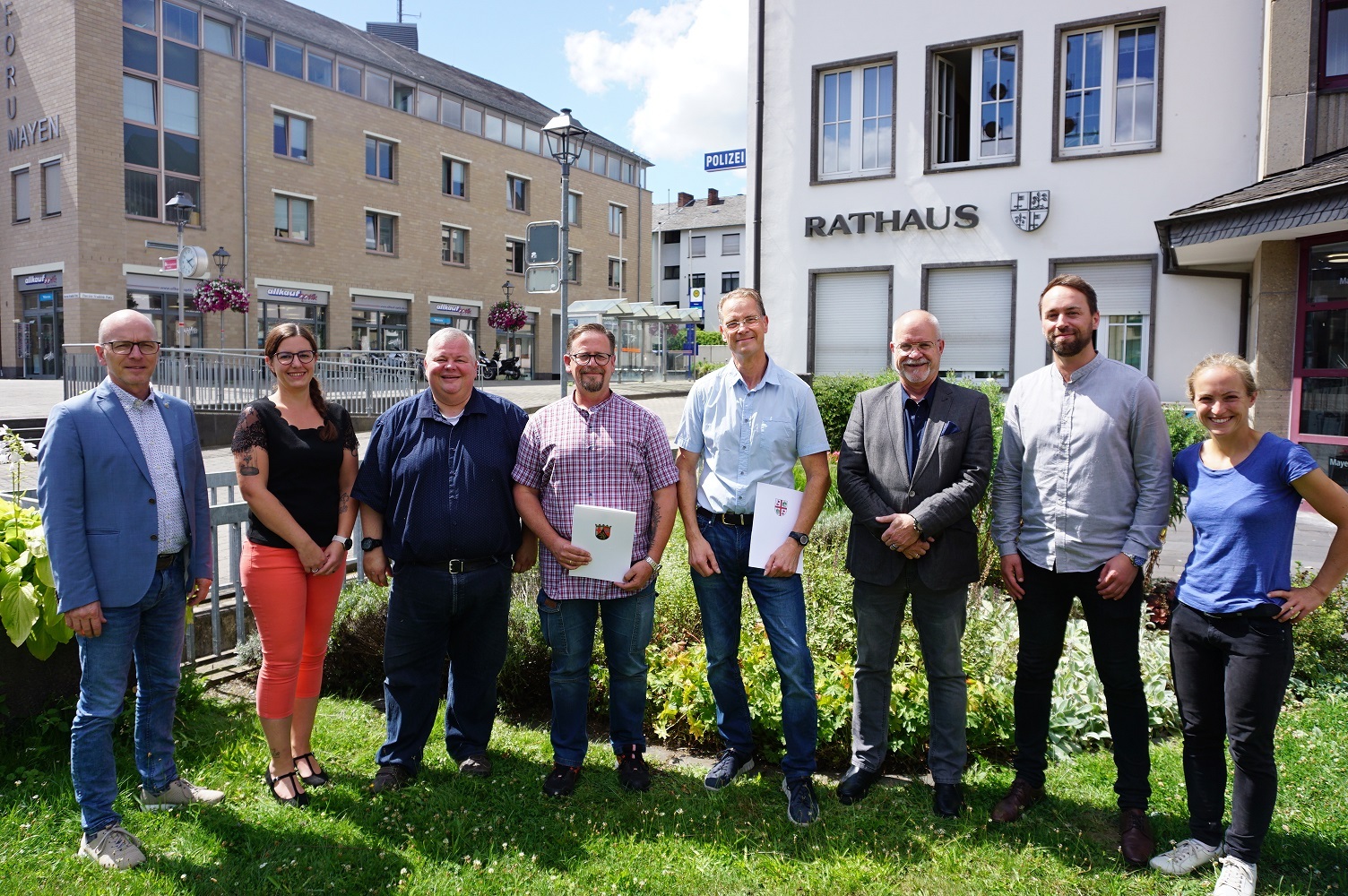 8 Personen stehen vor dem Rathaus