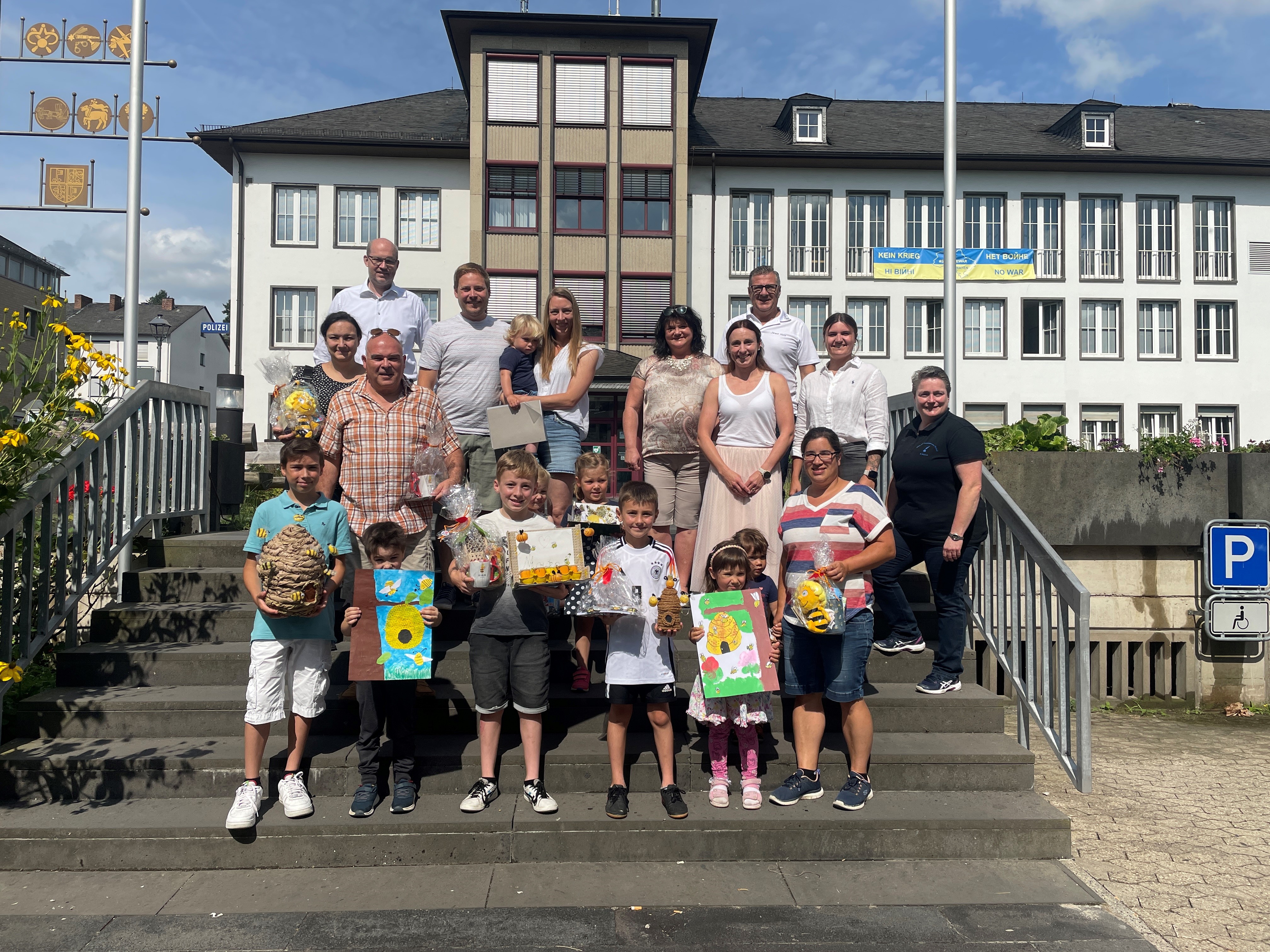 Zahlreiche Erwachsene und Kinder stehen auf der Treppe vor dem Rathaus - einige haben verschiedene Preise in der Hand
