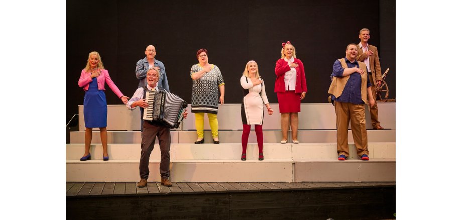 Mehrere Personen stehe auf einer Bühne und singen