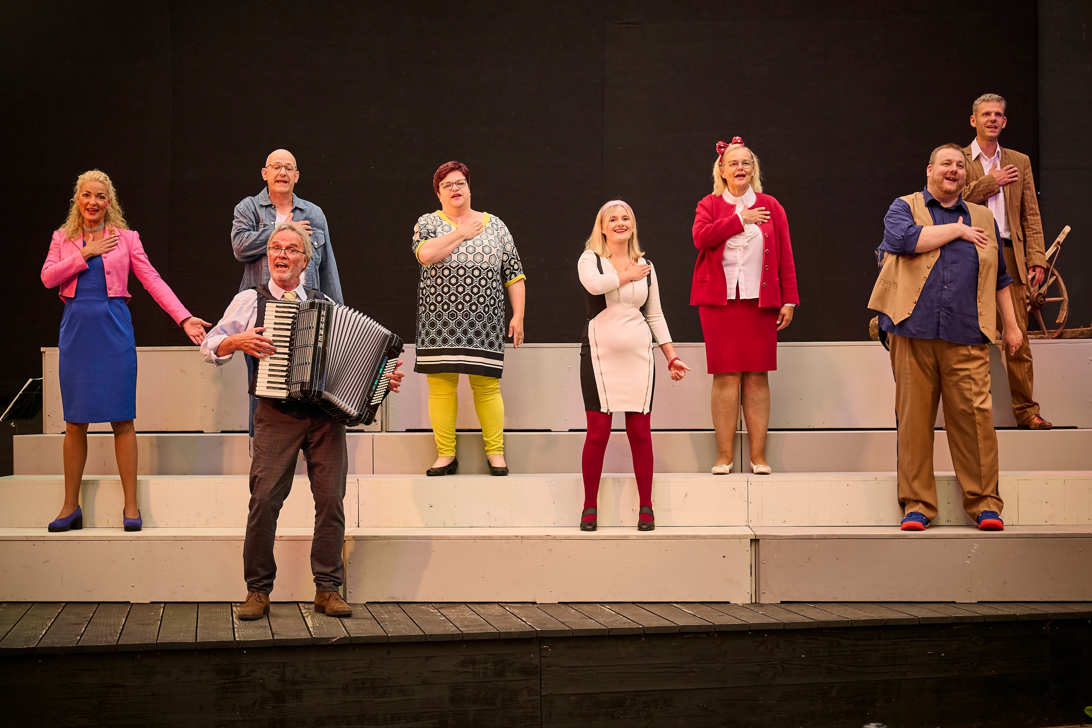 Mehrere Personen stehe auf einer Bühne und singen