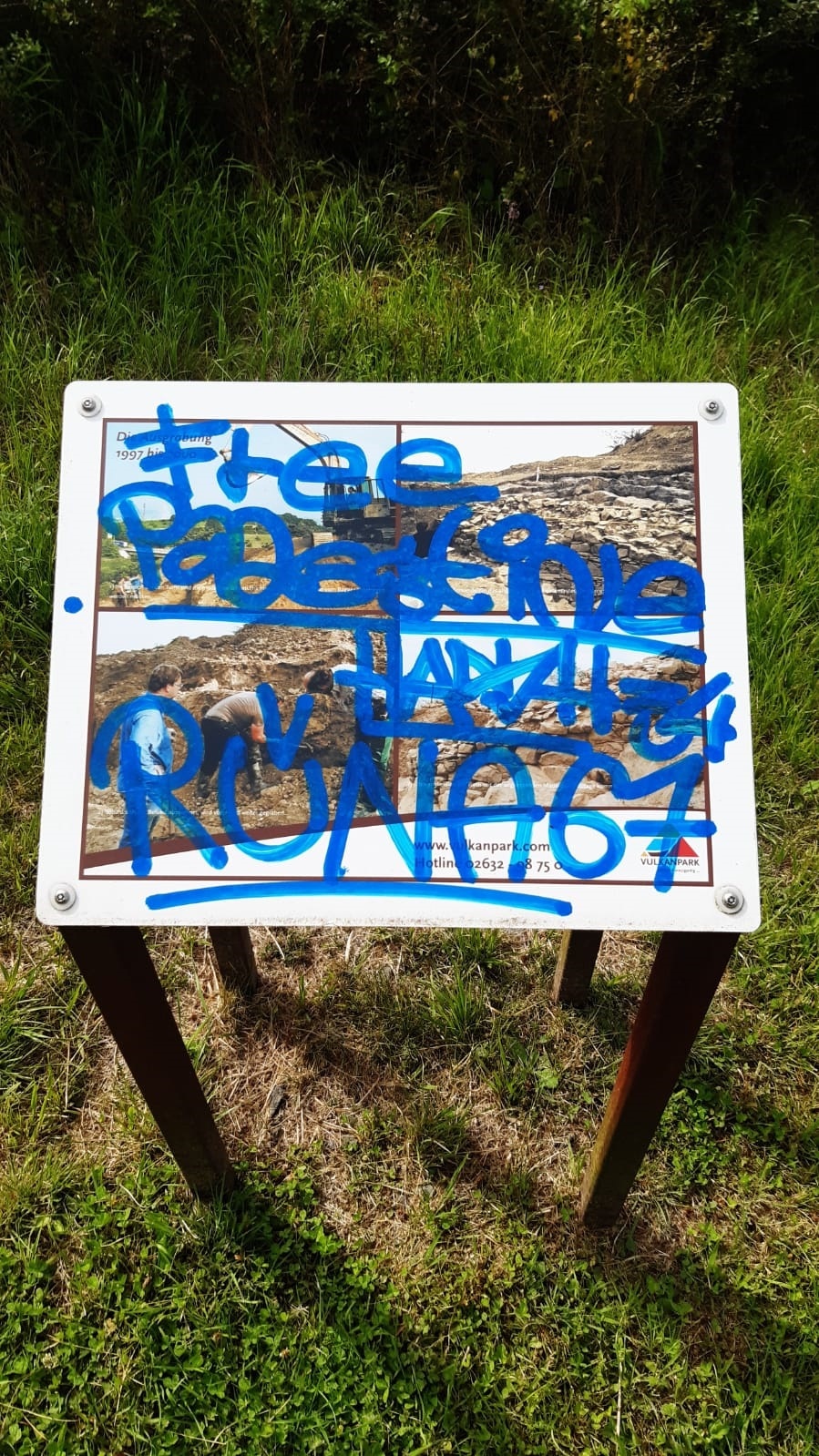 Hinweisschild mit Graffiti besprüht