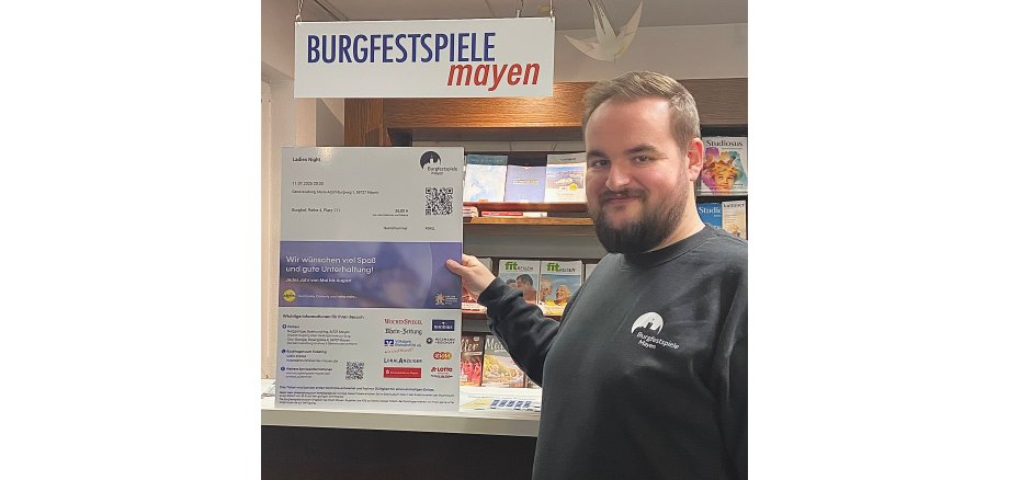 Verwaltungsleiter Kevin Stoye freut sich über das neue Ticketsystem Verwaltungsleiter Kevin Stoye vor einem Plakat zu dem neuen Ticketsystem