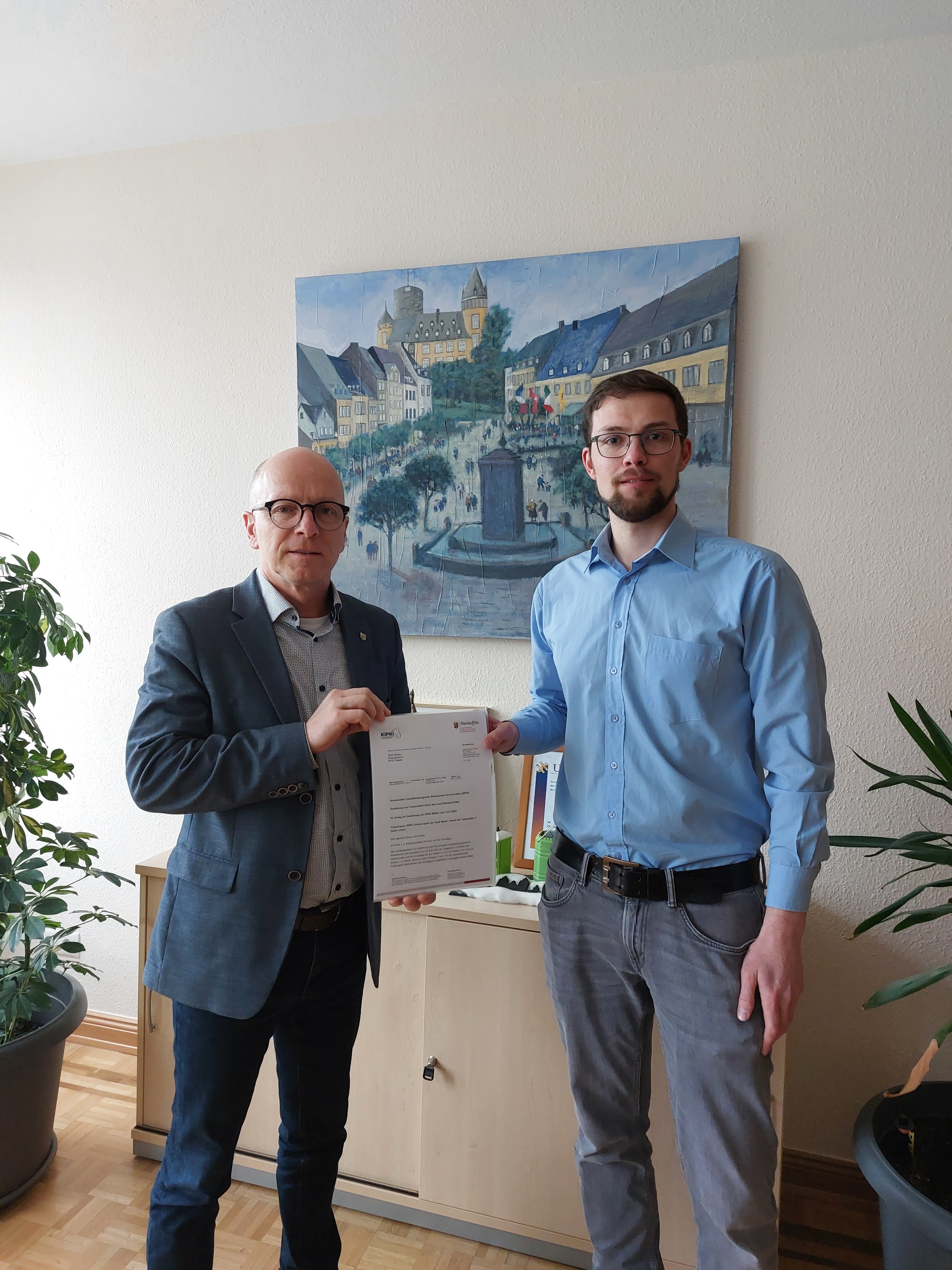 2 Personen stehen mit einem Bescheid in den Händen zusammen