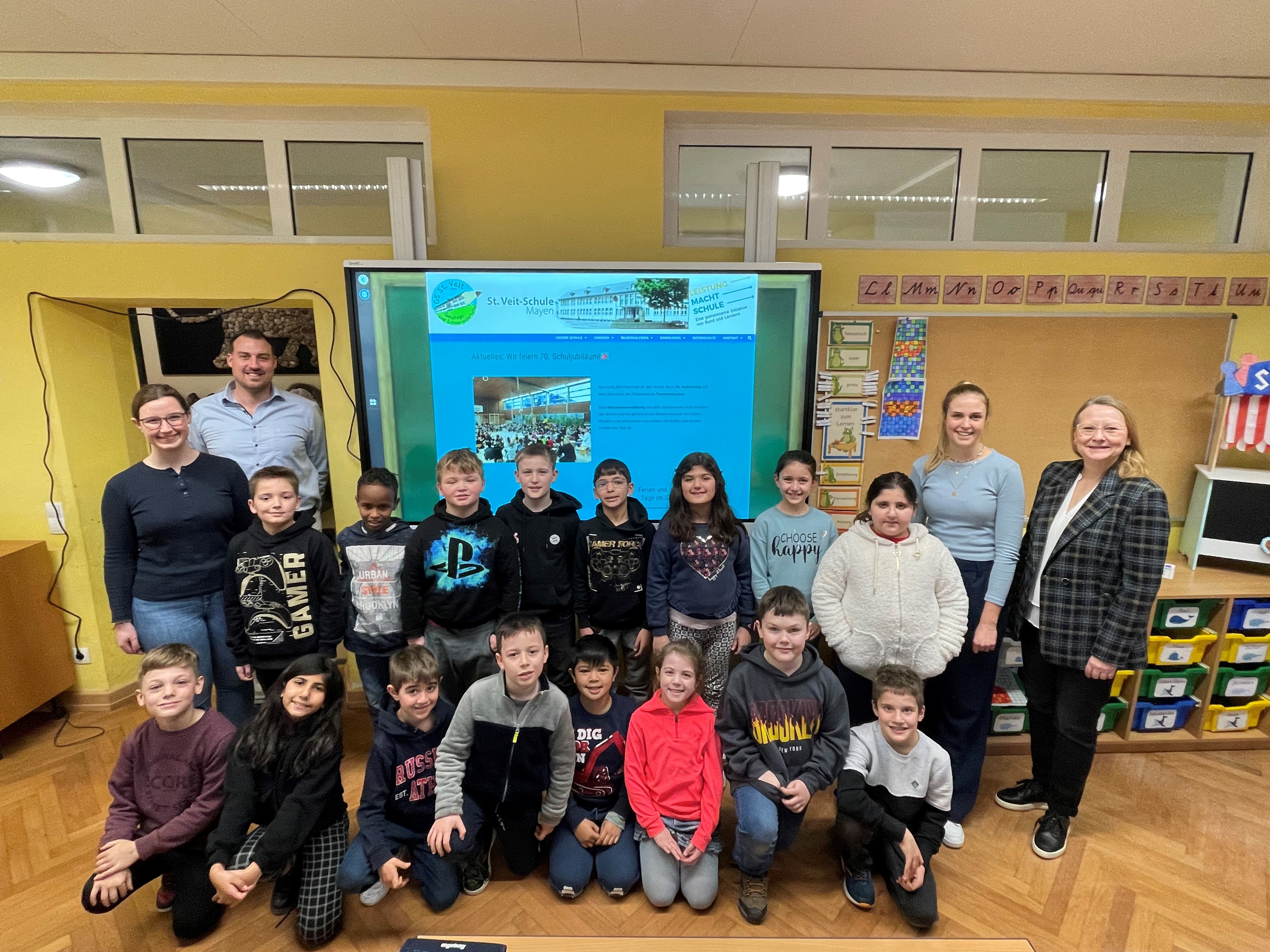 Mehrere Personen und Kinder vor dem neuen Smartboard im Klassenzimmer