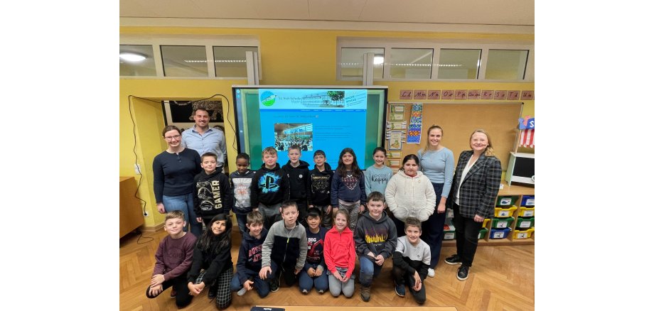 Mehrere Personen und Kinder vor dem neuen Smartboard im Klassenzimmer