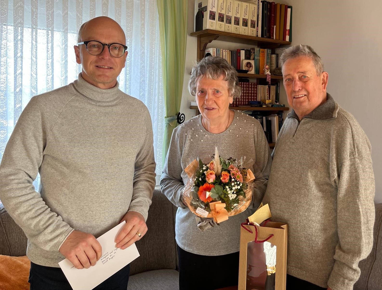 3 Personen - in der Mitte eine Frau mit einem Blumenstrauß