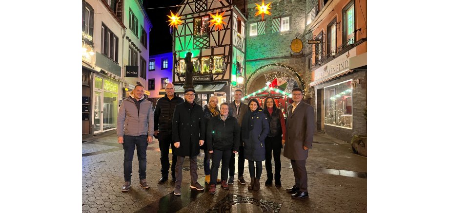 9 Personen stehen vor weihnachtlichem Ambiente zu einem Foto zusammen