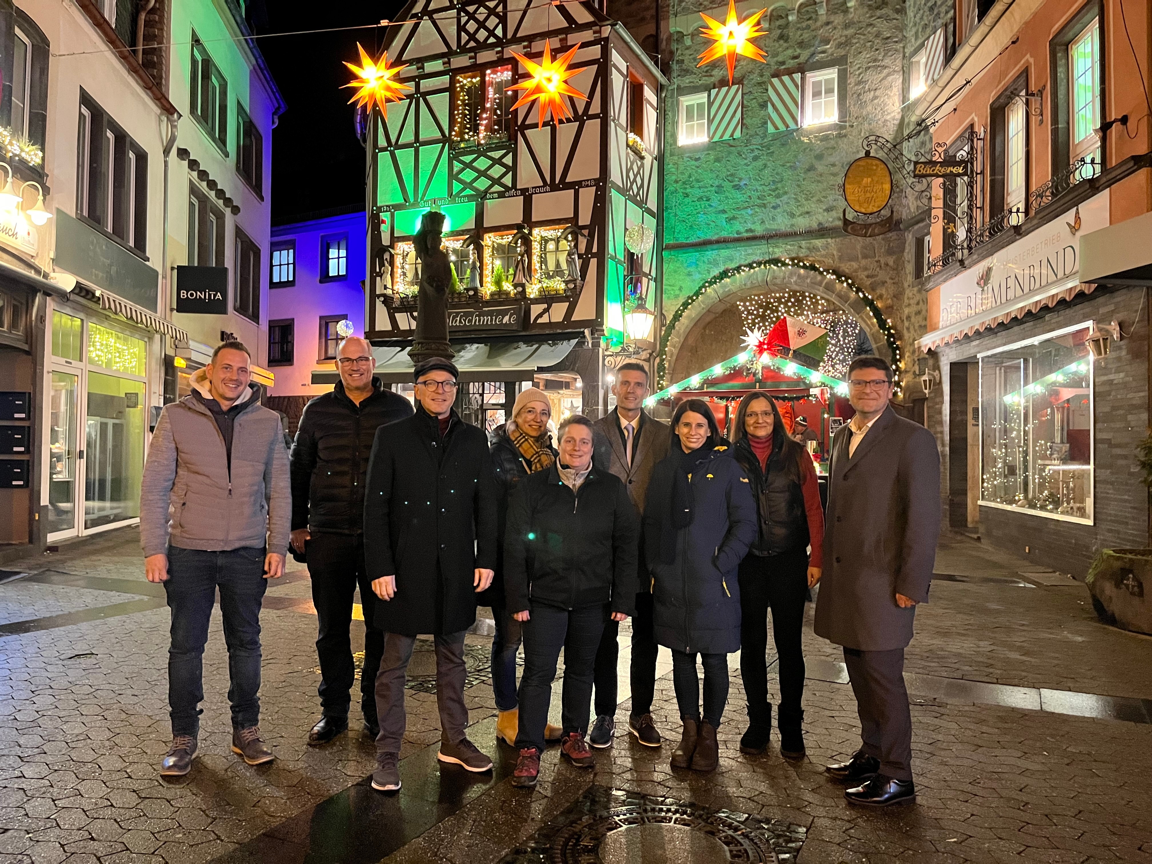 9 Personen stehen vor weihnachtlichem Ambiente zu einem Foto zusammen