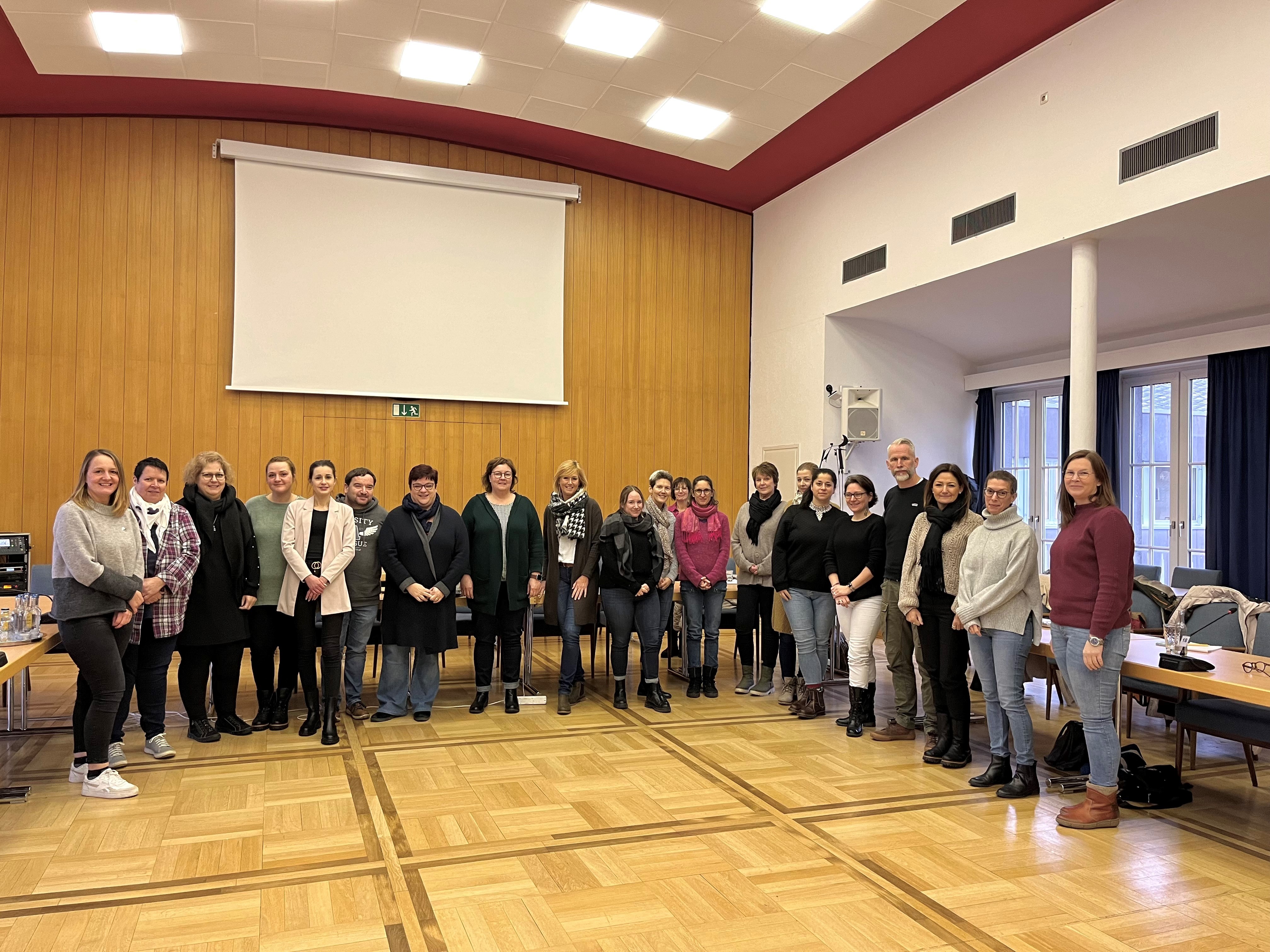 Mehrere Personen stehen in einem Saal zu einem Gruppenbild zusammen