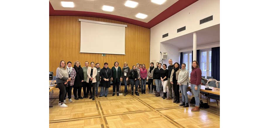 Mehrere Personen stehen in einem Saal zu einem Gruppenbild zusammen