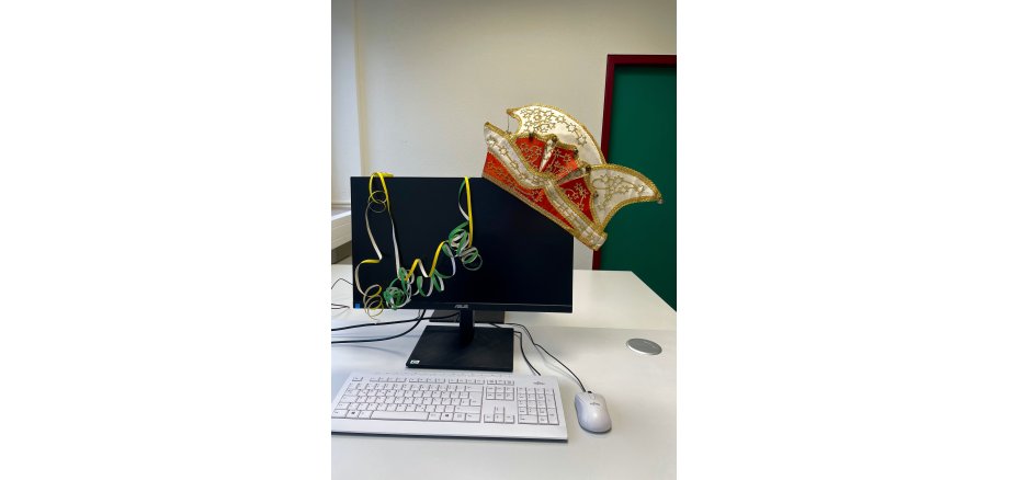 Öffnungszeiten der Stadtverwaltung an Karneval Narrenkappe und Luftschlangen hängen an einem Bildschirm