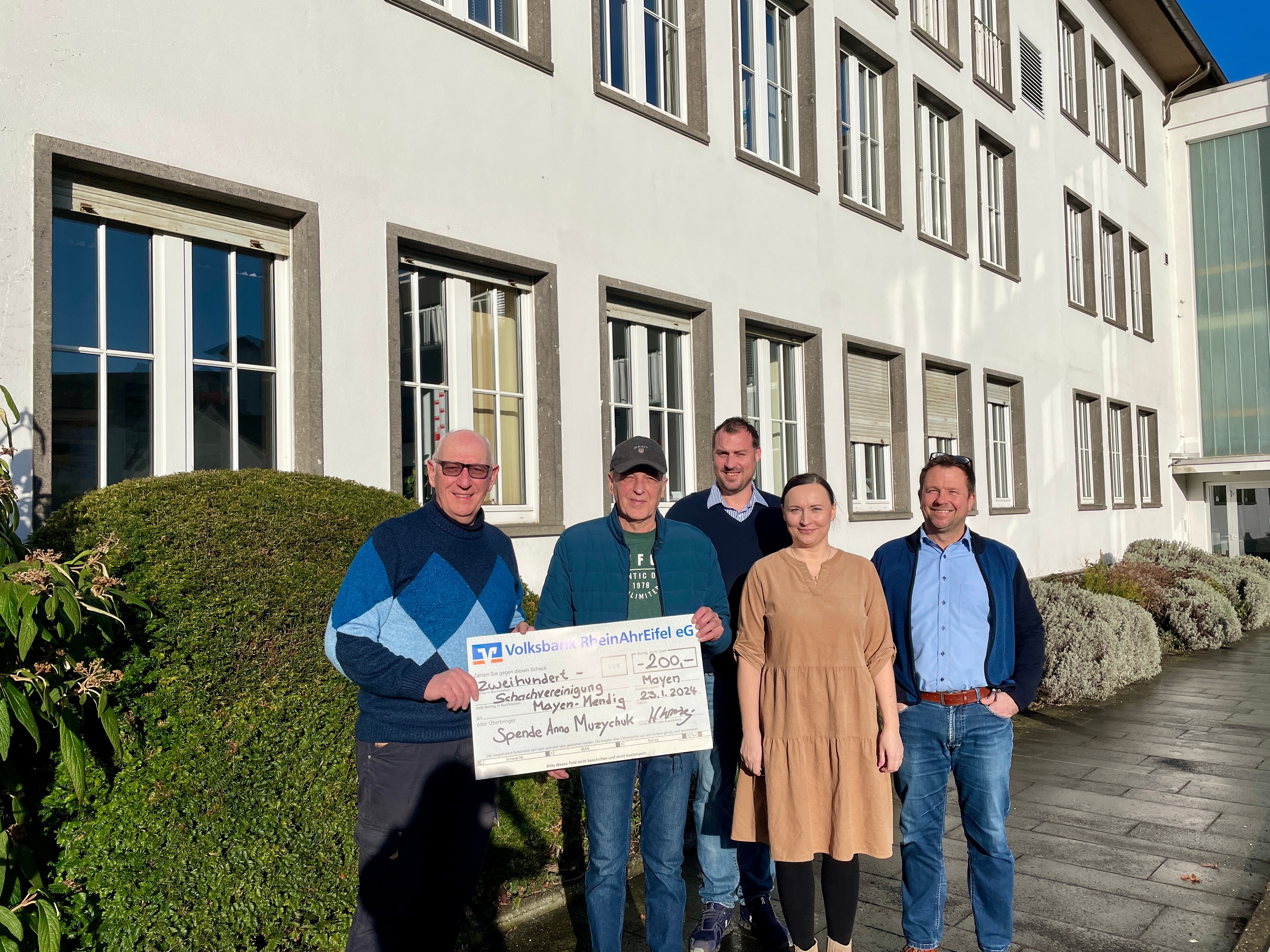 5 Personen stehen für ein Bild zusammen - 2 halten einen Scheck über 200€ in den Händen