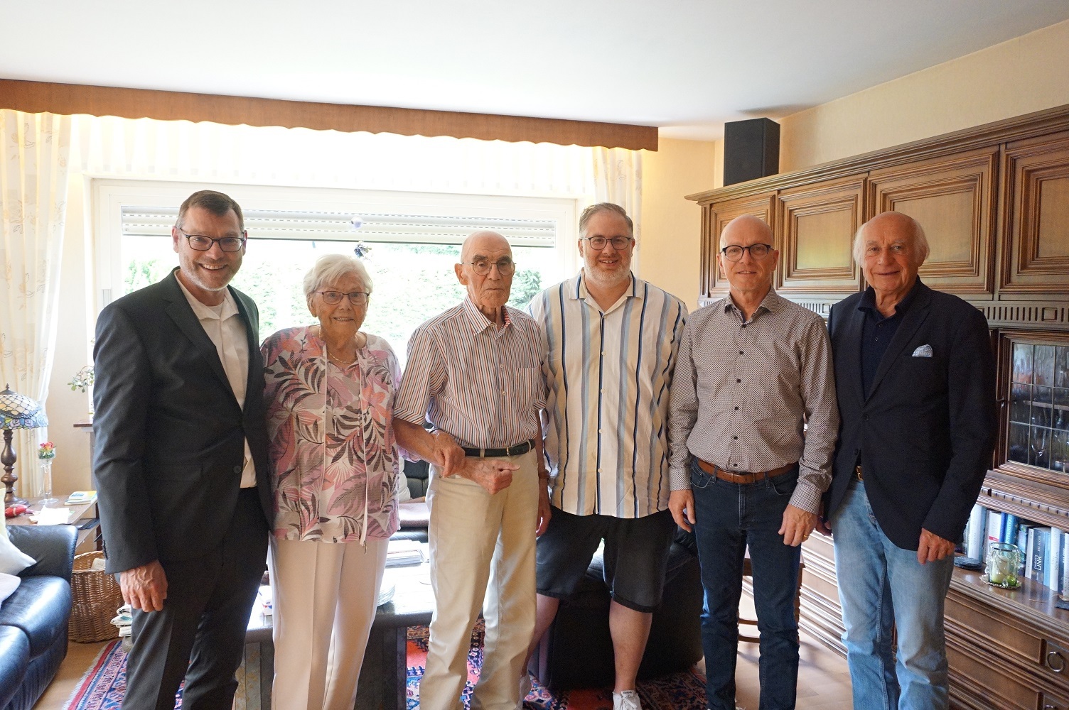 6 Personen stehen in einem Wohnzimmer für ein Foto zusammen