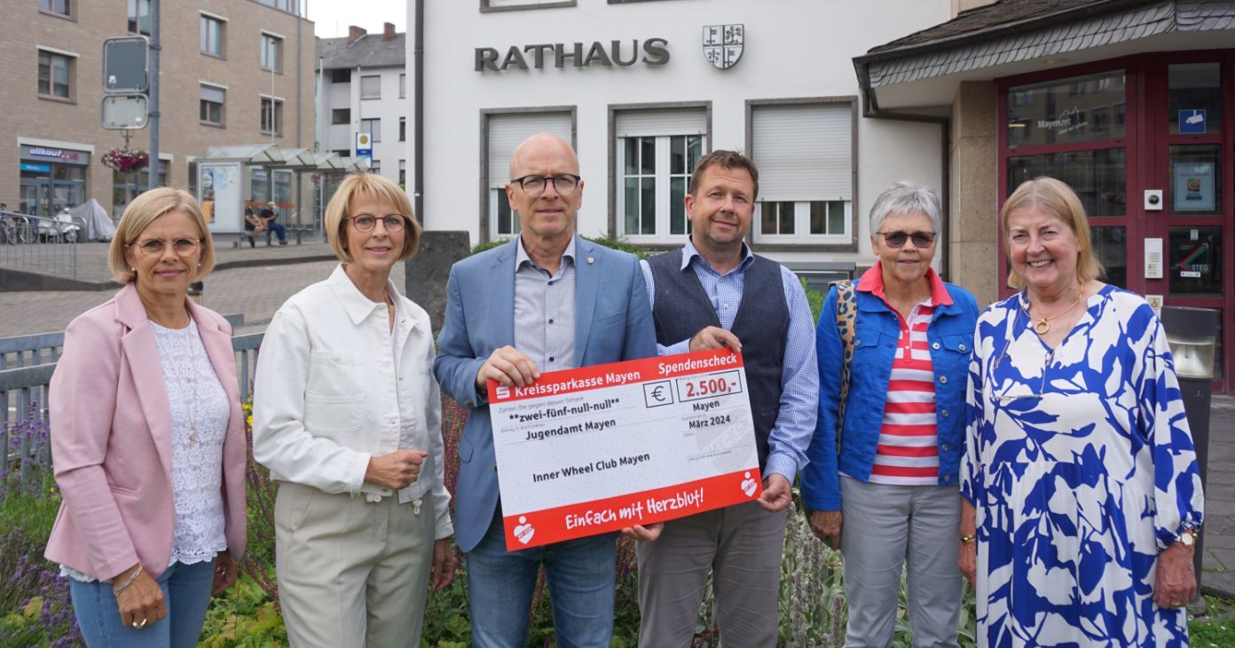 Sechs Personen mit Spendenscheck vor dem Rathaus